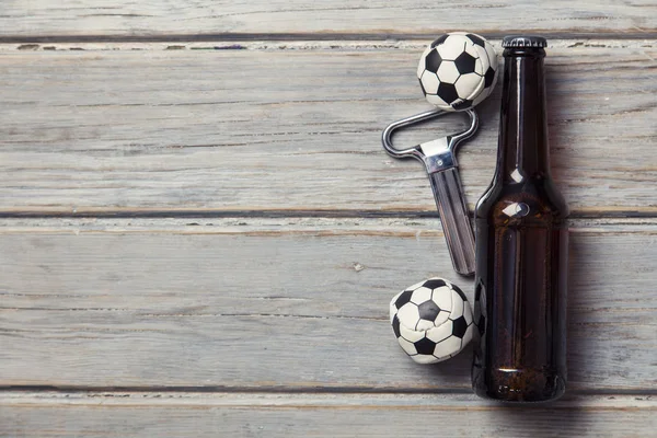Beer bottle with soccer football balls on a wooden background