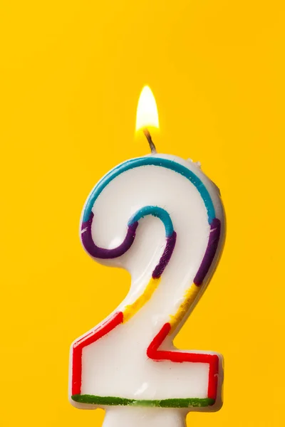 Numero 2 candela celebrazione di compleanno contro un luminoso bac giallo — Foto Stock