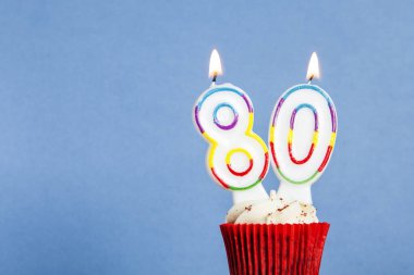 Mavi bir arka plan aleyhine bir cupcake sayısı 80 doğum günü mum
