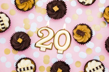 Bir pastel pembe backgr karşı cupcakes ile Sayı 20 altın mum