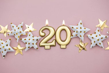 20 numara altın mum ve pastel pembe arka plan üzerinde yıldız