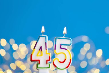 Number 45 birthday celebration candle against a bright lights an clipart