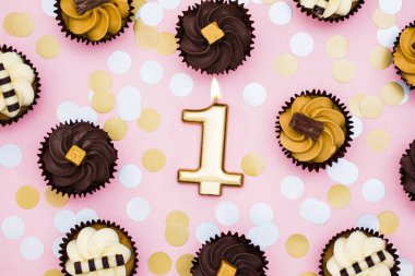Bir pastel pembe backgro karşı cupcakes ile Sayı 1 altın mum