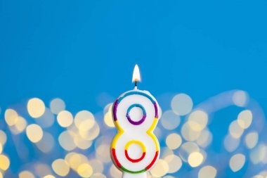 Number 8 birthday celebration candle against a bright lights and clipart
