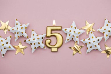 5 numara altın mum ve pastel pembe arka plan üzerinde yıldız