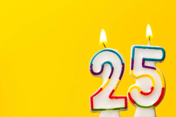 Número 25 aniversário celebração vela contra um ba amarelo brilhante — Fotografia de Stock