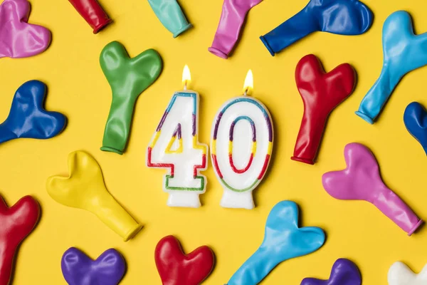 Number 40 candle with party balloons on a bright yellow backgrou — Stock Photo, Image