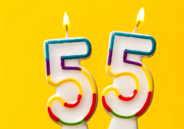 Number 55 birthday celebration candle against a bright yellow ba — Stock Photo, Image