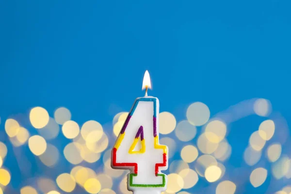 Number 4 birthday celebration candle against a bright lights and — Stock Photo, Image