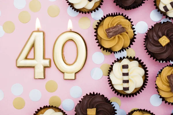 Vela dorada número 40 con cupcakes contra un fondo rosa pastel —  Fotos de Stock