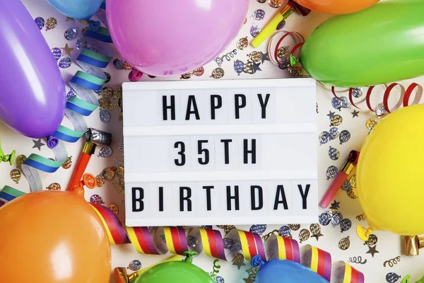 Happy 35th birthday celebration message on a lightbox with ballo — Stock Photo, Image