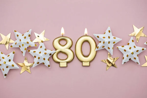Szám 80 arany gyertya és csillagok a pasztell rózsaszín háttér — Stock Fotó