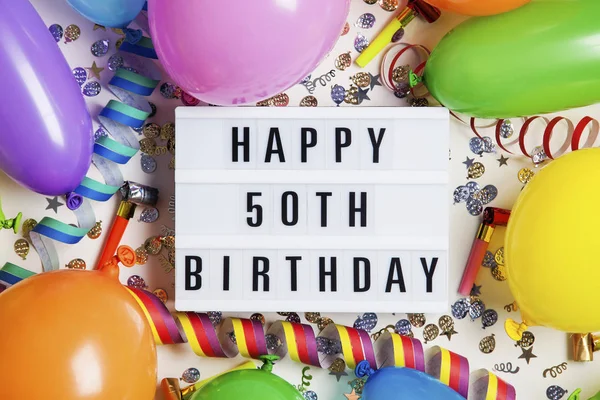 Happy 50th birthday celebration message on a lightbox with ballo — Stock Photo, Image