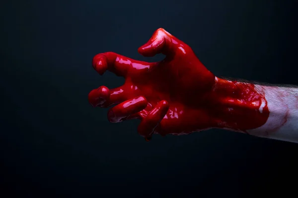 Bloedige hand tegen een donkere achtergrond. Halloween Horror concept — Stockfoto