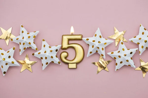 Číslo 5 zlaté svíčky a hvězdy na pastelově růžovém pozadí — Stock fotografie