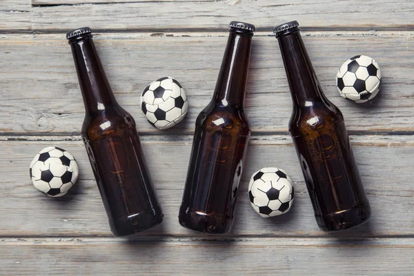 Bier fles met voetbal ballen op een houten achtergrond — Stockfoto