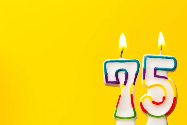 Numara 75 parlak sarı ba karşı doğum günü kutlama mum — Stok fotoğraf