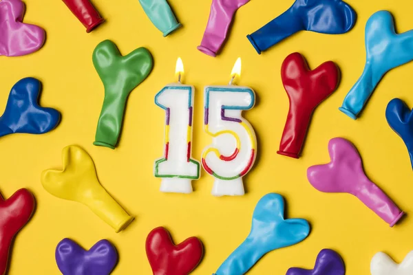 Vela número 15 com balões de festa em um backgrou amarelo brilhante — Fotografia de Stock