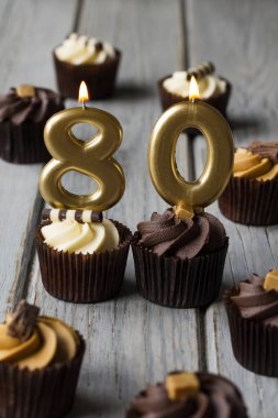 Number 80 celebration birthday cupcakes on a wooden background clipart
