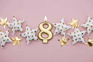 8 numara altın mum ve pastel pembe arka plan üzerinde yıldız