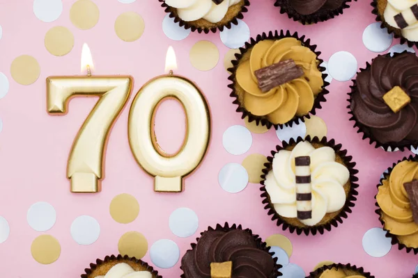 Vela dorada número 70 con cupcakes contra un fondo rosa pastel —  Fotos de Stock