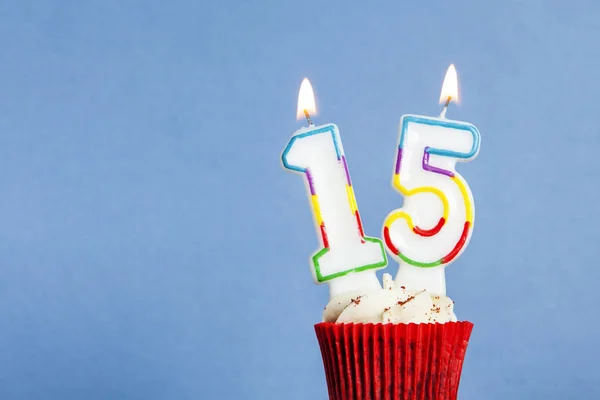 Bougie d'anniversaire numéro 15 dans un cupcake sur un fond bleu — Photo