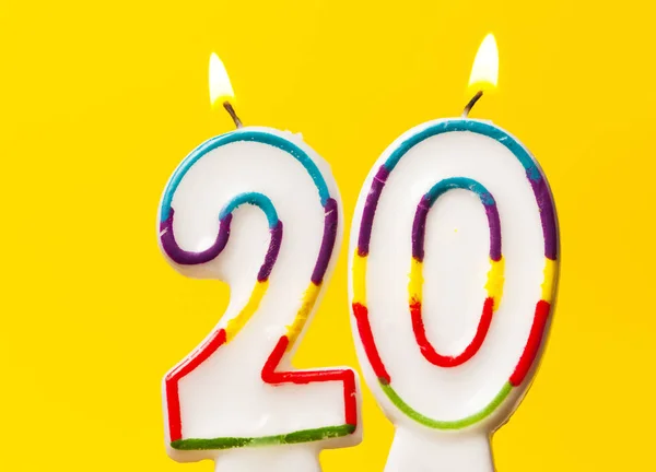Свеча для празднования дня рождения номер 20 против ярко-желтой — стоковое фото