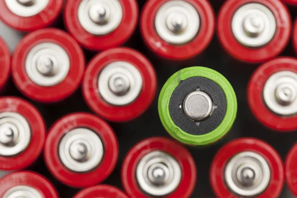 Zielona bateria wyróżnia się z czerwonymi bateriami. Zielona energia SUP — Zdjęcie stockowe