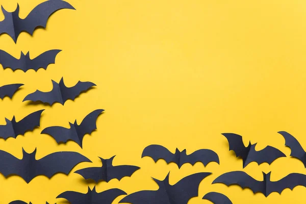 Halloween paper vampire bat decorations on an orange background.