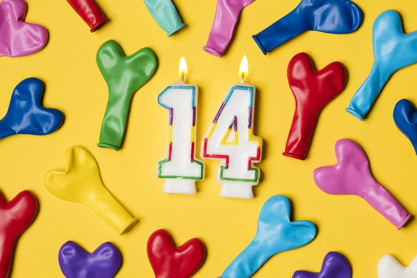 Vela número 14 com balões de festa em um backgrou amarelo brilhante — Fotografia de Stock