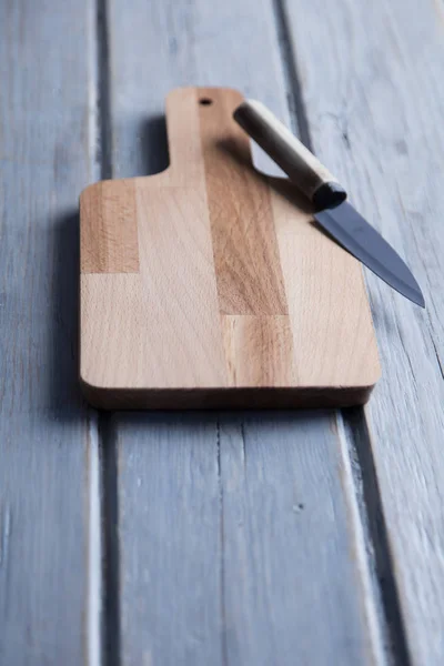 Wooden chopping board and knife on a rustic wood plank backgroun