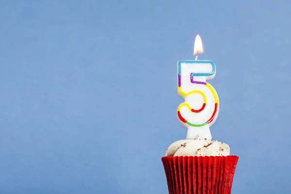 Vela de cumpleaños número 5 en un cupcake sobre un fondo azul —  Fotos de Stock