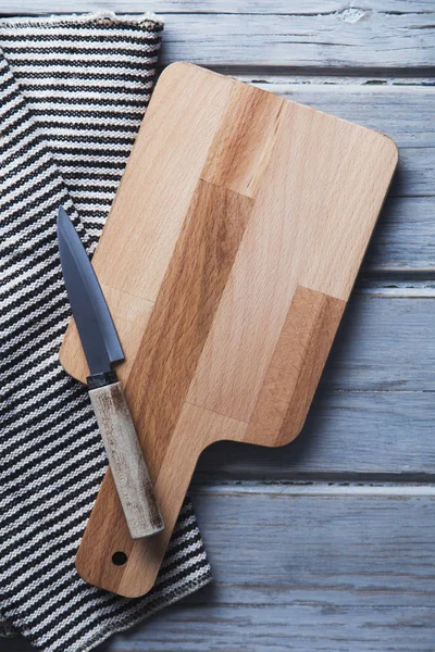 Wooden chopping board and cloth on a rustic wood plank table — Stock Photo, Image