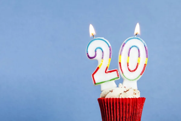 Vela de aniversário número 20 em um cupcake contra um fundo azul — Fotografia de Stock