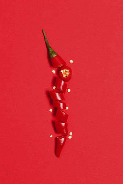 Κόκκινη πιπεριά τσίλι σε φέτες, τοποθετημένα σε φωτεινό κόκκινο φόντο — Φωτογραφία Αρχείου
