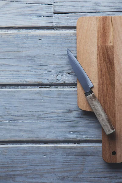 Wooden chopping board and knife on a rustic wood plank backgroun