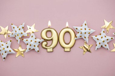 Numara 90 altın mum ve pastel pembe arka plan üzerinde yıldız