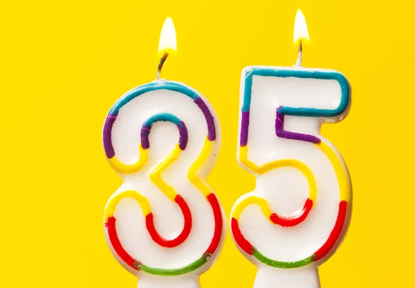 Number 35 birthday celebration candle against a bright yellow ba — Stock Photo, Image