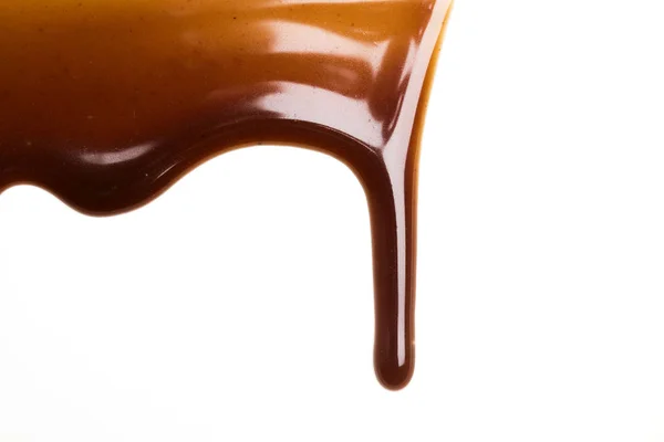 Шоколадний карамельний соус падає на звичайний білий фон — стокове фото