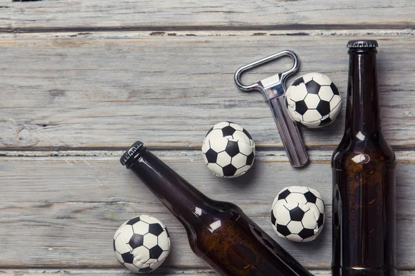 Bier fles met voetbal ballen op een houten achtergrond — Stockfoto