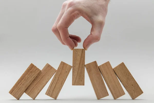 Mannelijke hand stoppen houten blokken vallen over — Stockfoto