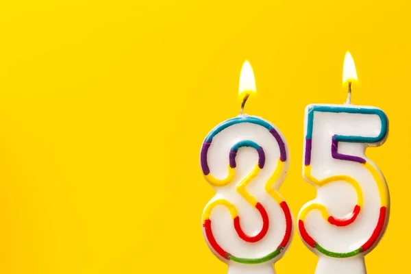 Number 35 birthday celebration candle against a bright yellow ba — Stock Photo, Image