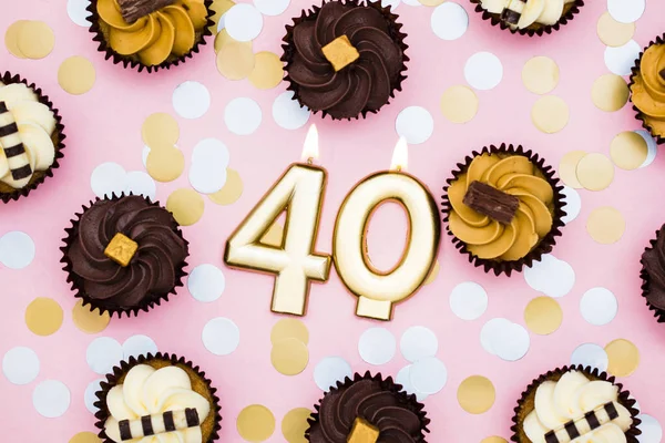 Vela dorada número 40 con cupcakes contra un fondo rosa pastel —  Fotos de Stock