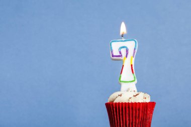 Mavi bir arka plan aleyhine bir cupcake içinde Numara 7 doğum günü mum