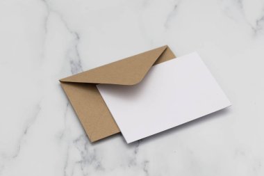 Mermer backg üzerinde kraft kahverengi kağıt zarf ile boş beyaz kart