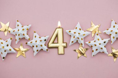 4 numara altın mum ve pastel pembe arka plan üzerinde yıldız