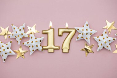 17 numara altın mum ve pastel pembe arka plan üzerinde yıldız