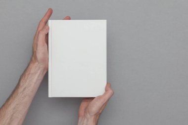 Erkek elinin elinde kitap kapağını gösteren kapalı bir kitap tutuyor. Kitap Moc