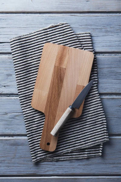 Wooden chopping board and cloth on a rustic wood plank table
