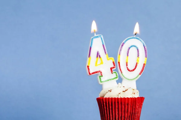 Number 40 birthday candle in a cupcake against a blue background